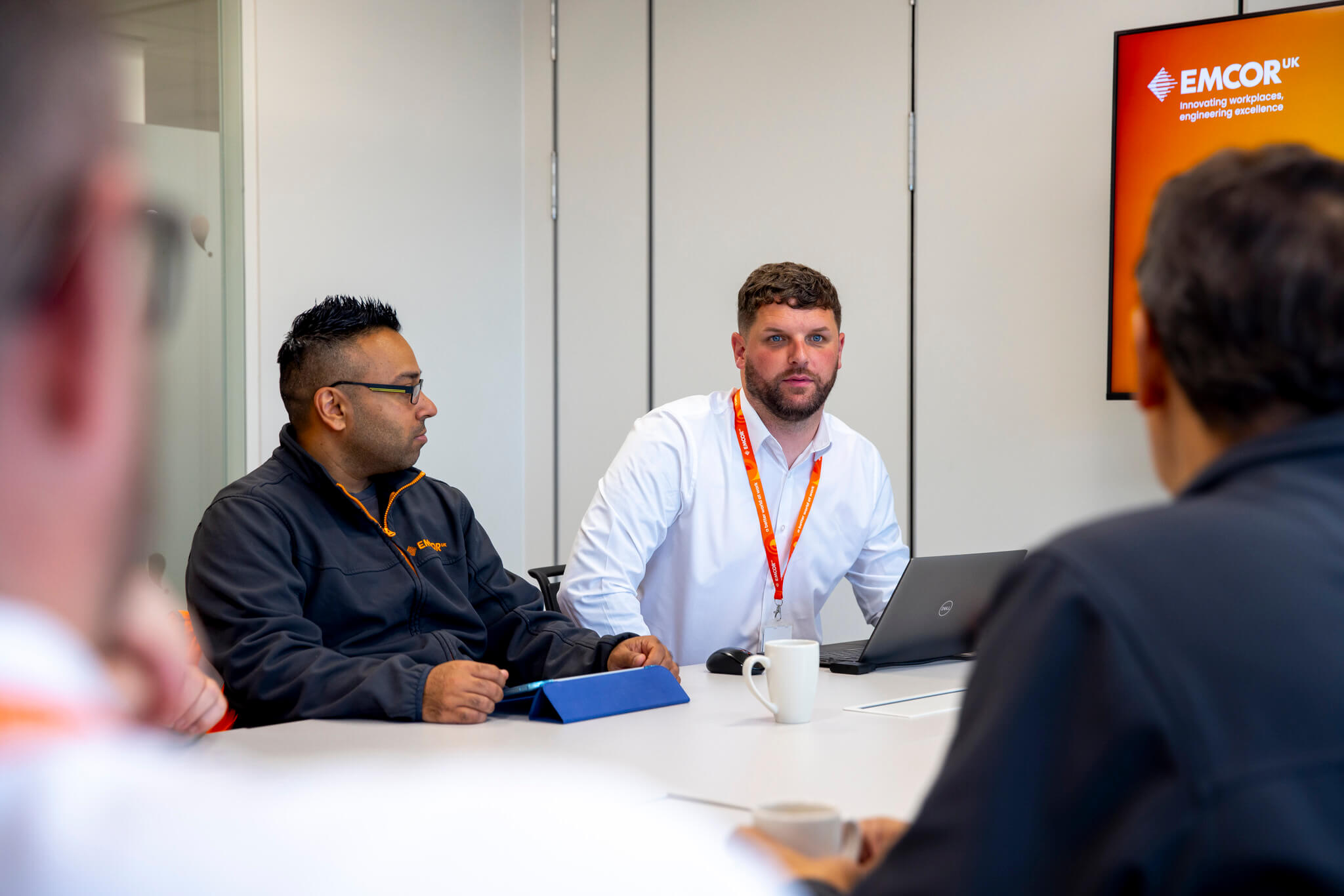 Four male colleagues sat around a large table having a meeting. 