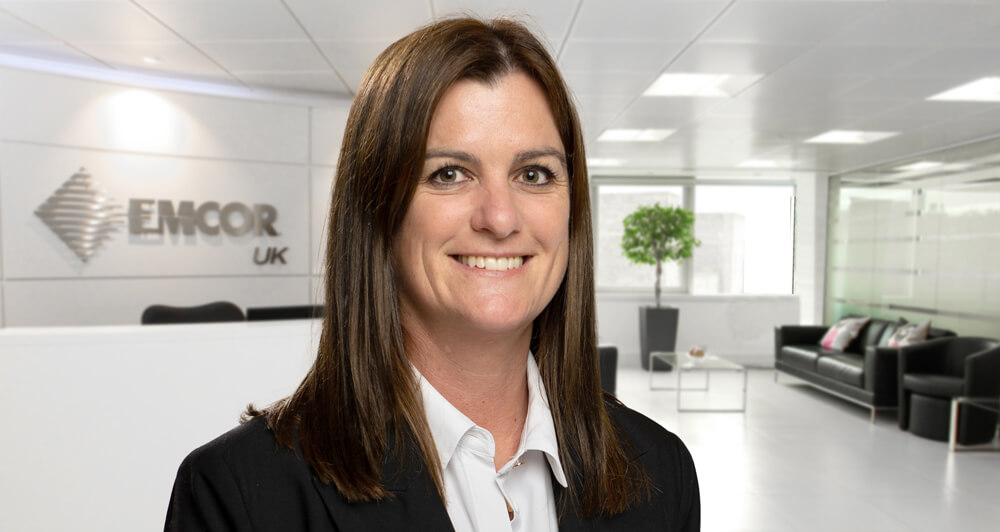 Profile picture of EMCOR UK's CFO Cheryl McCall with the EMCO RUK lobby in the background.