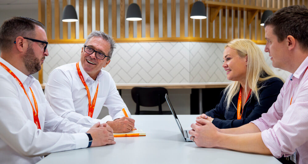 four EMCOR UK colleagues sitting in a communal workspace