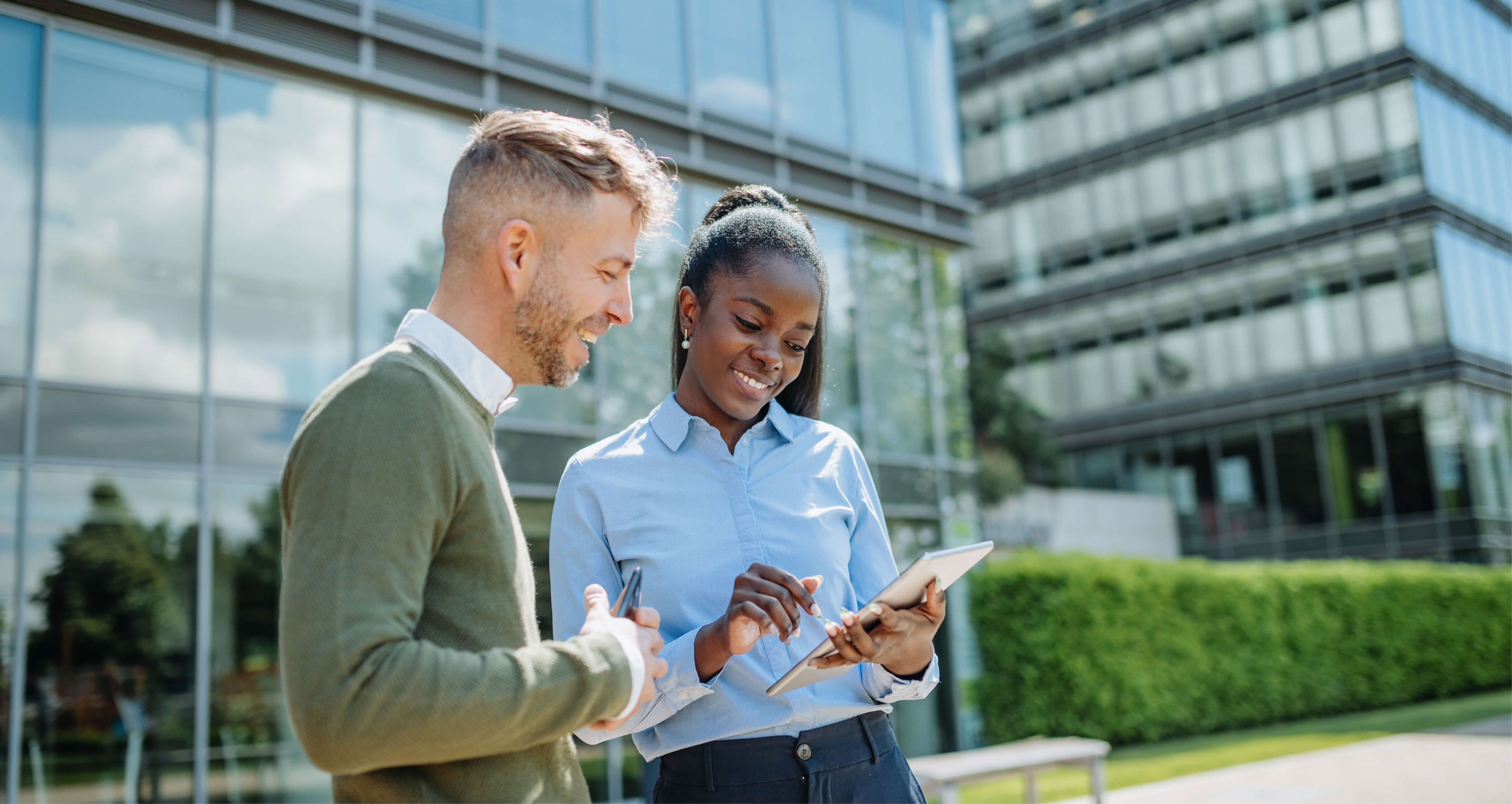 Two EMCOR UK colleagues standing outside of an office building looking at a tablet.