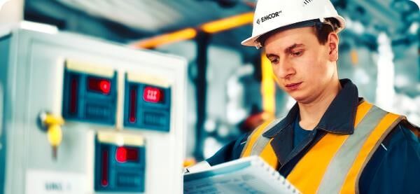 Man in PPE looking at a safety book in a plant room.