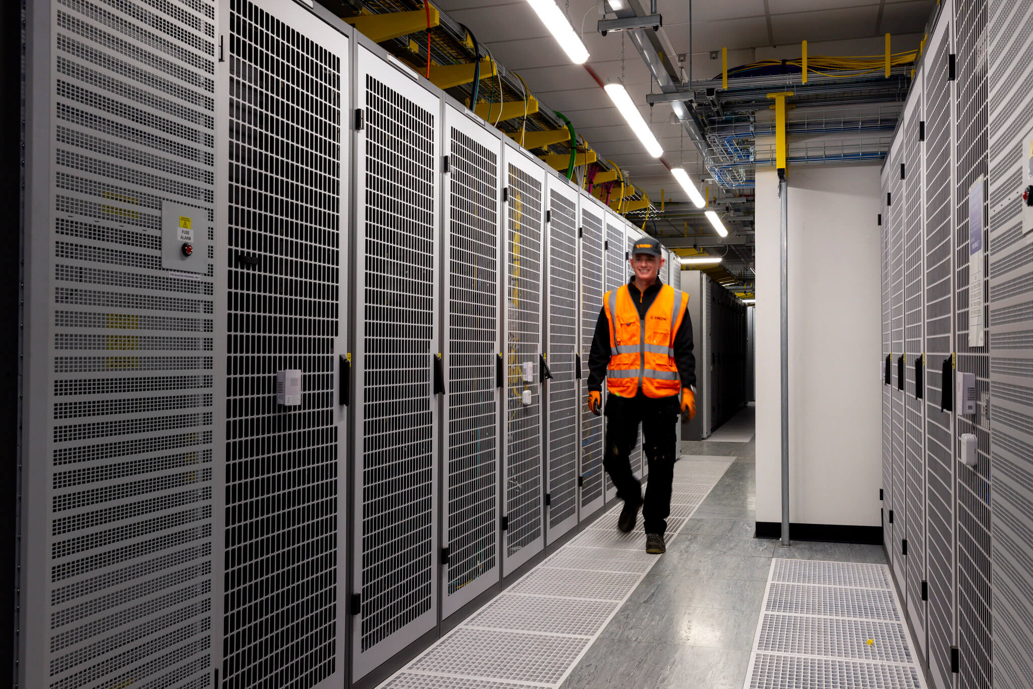 Engineer walking through corridor of a data centre facility. 