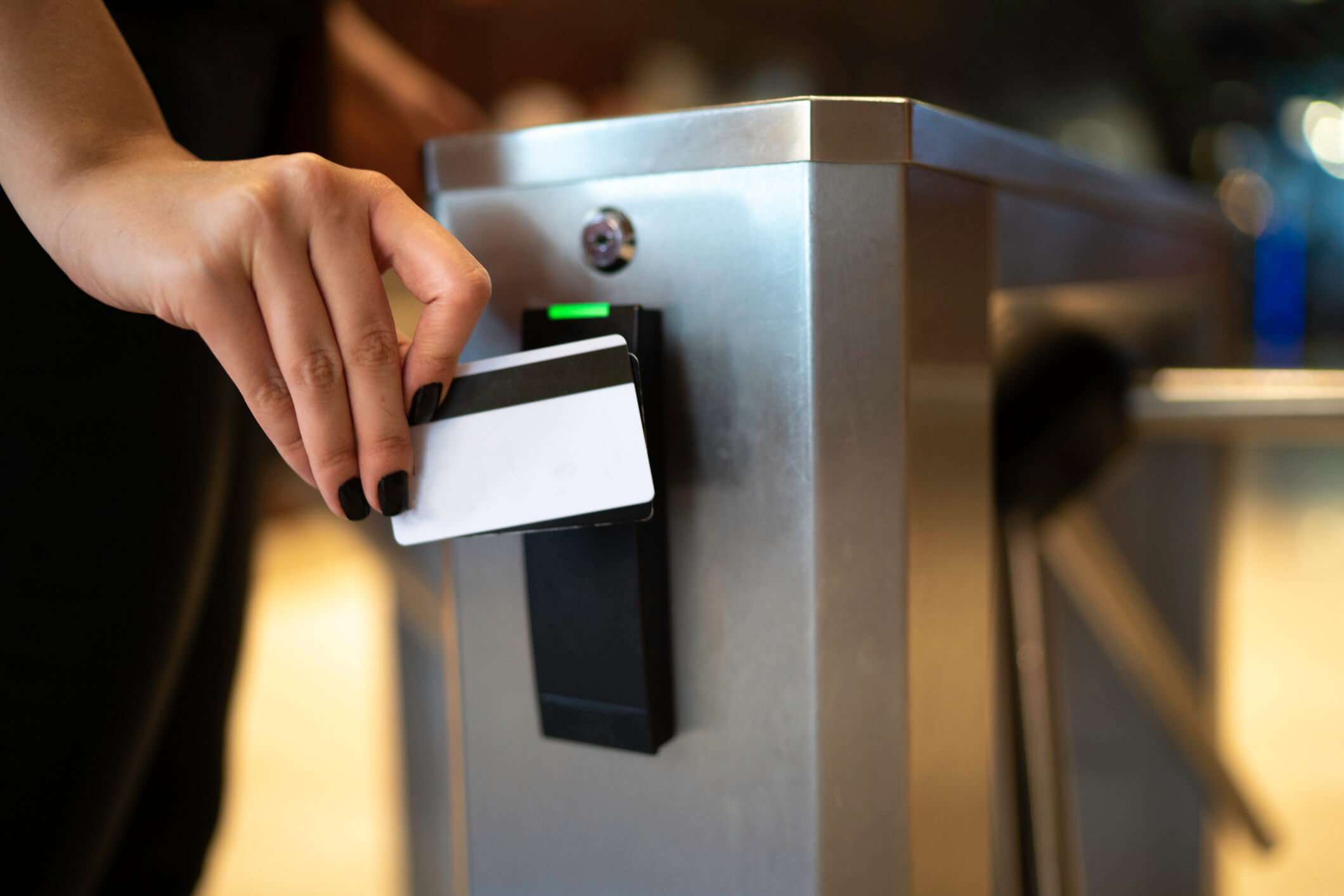 Person using card to scan through an automated security barrier. 