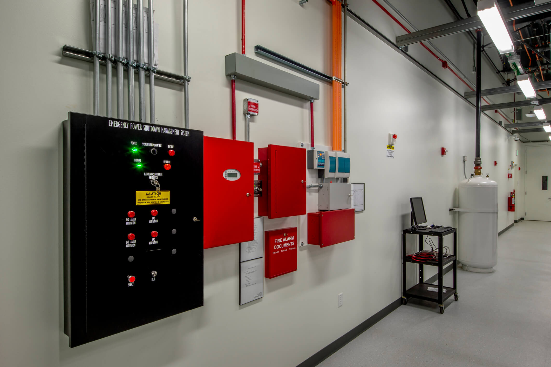 Industrial fire and security panel. Located in a clean corridor with a computer and boiler in the background. 