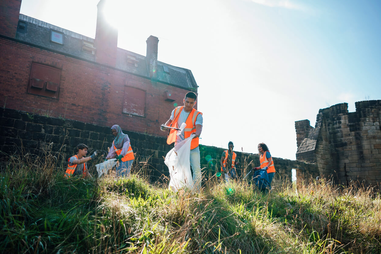 A group of volunteers litter-picking outside wearing hi-vis waistcoats. 