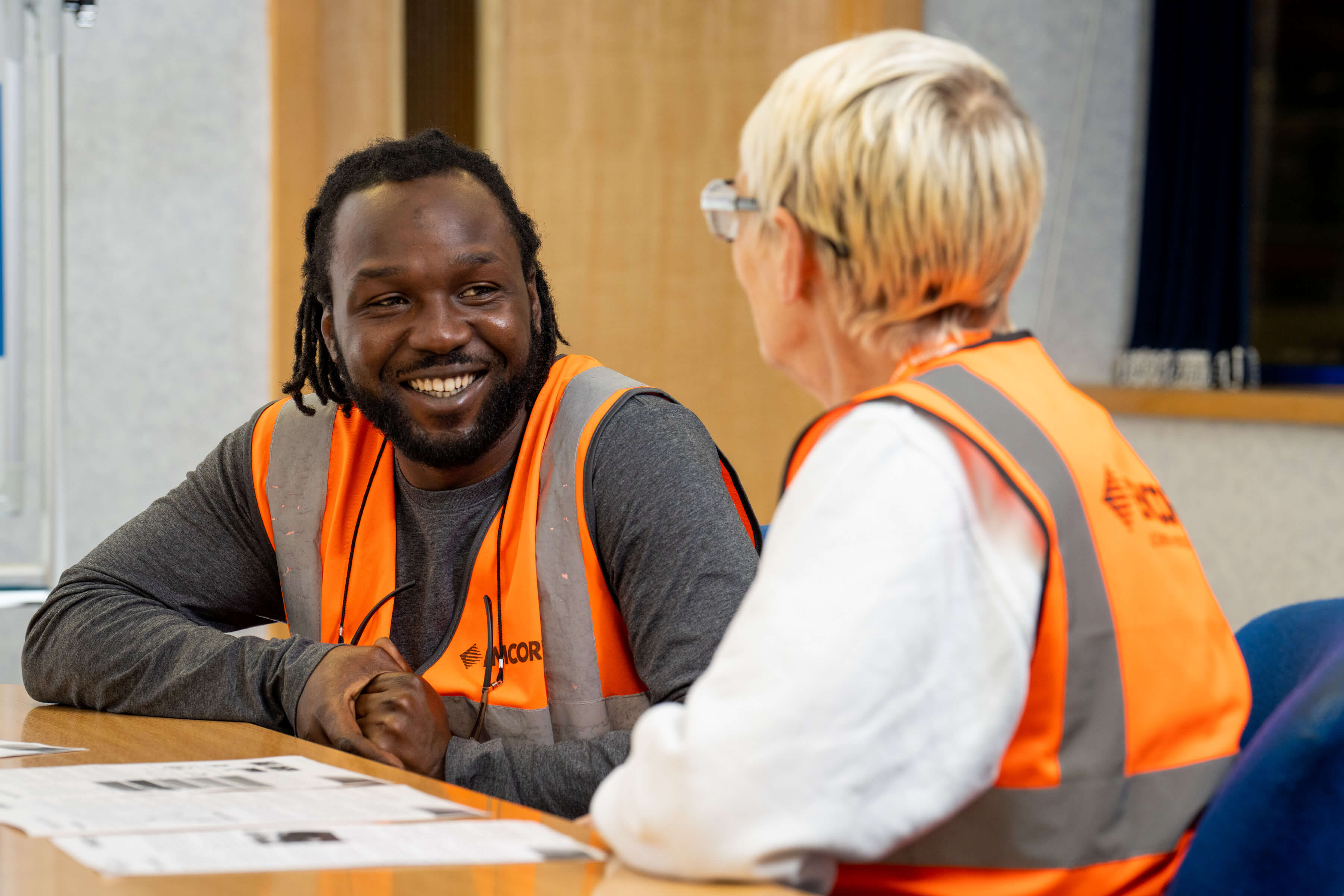 Male and female colleagues wearing EMCOR UK high vis talking in a meeting room