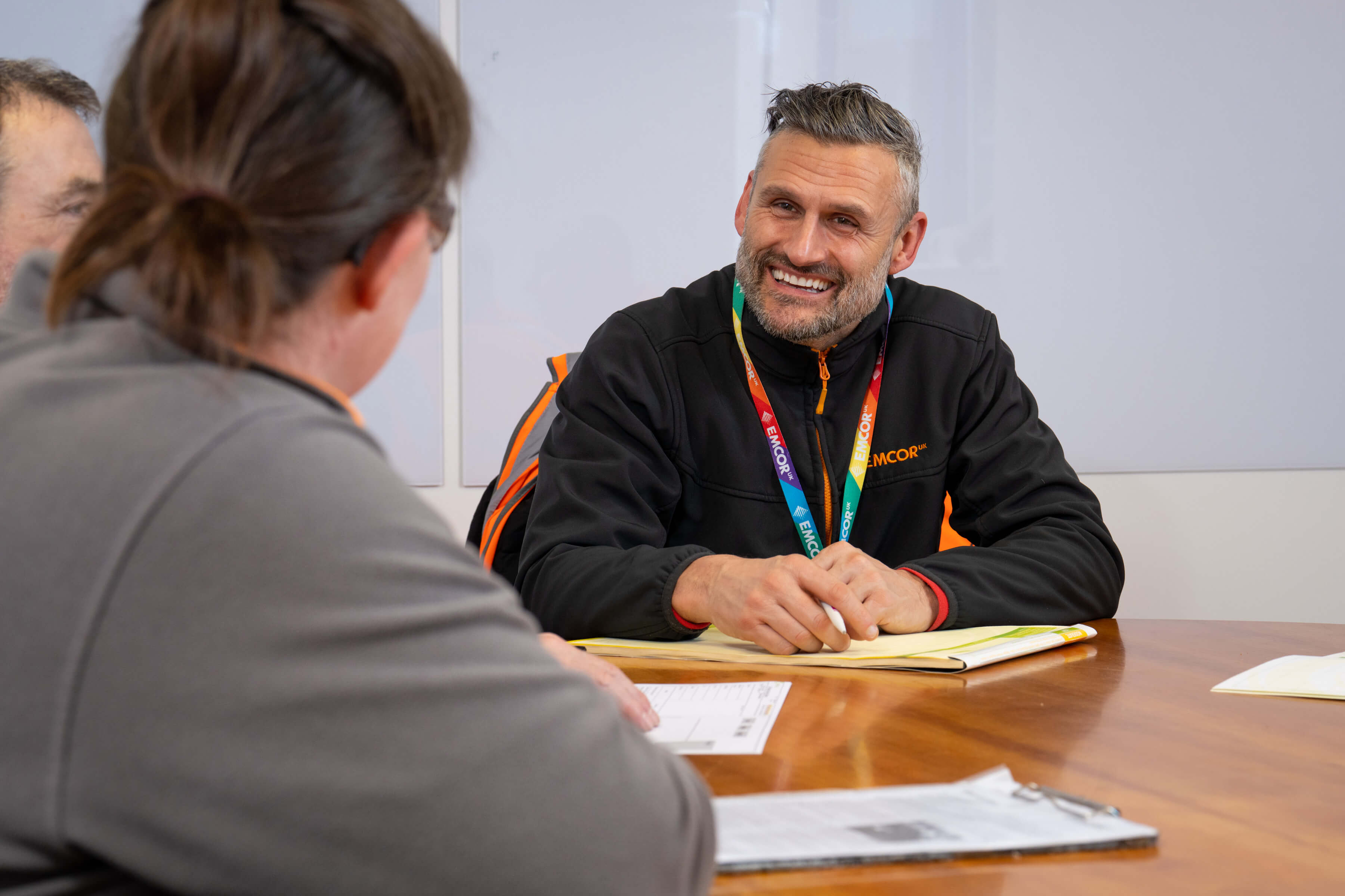 Two male and one female colleagues sat talking around a table with papers. 