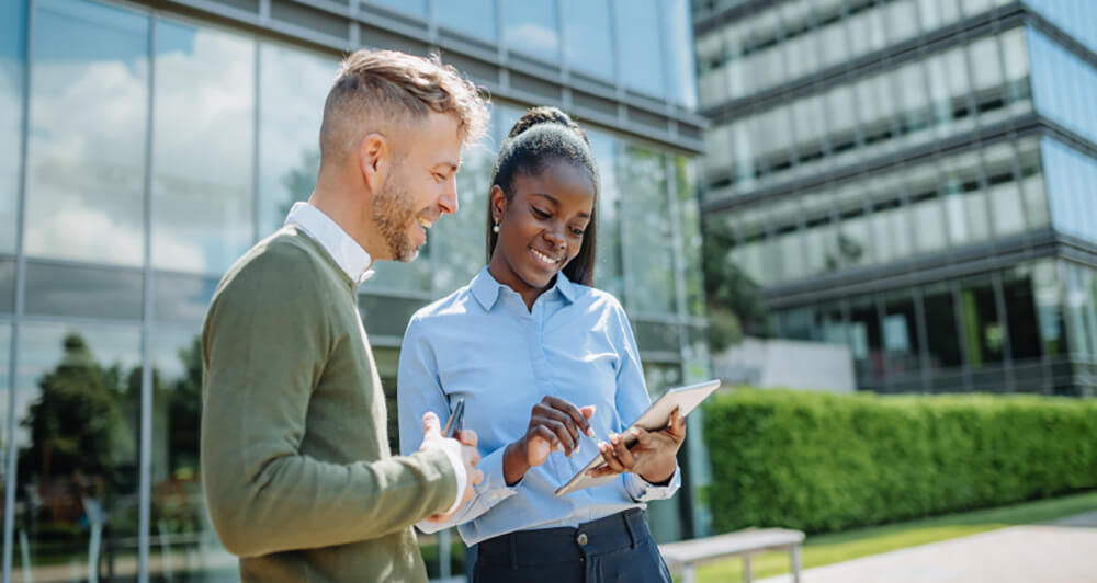 Two EMCOR UK coworkers standing outside looking at a tablet.