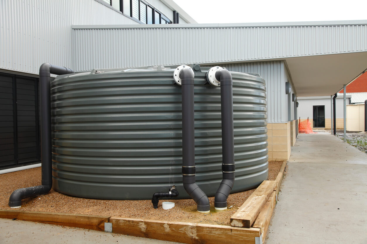 A large rainwater harvesting tank situated outside a facility building.